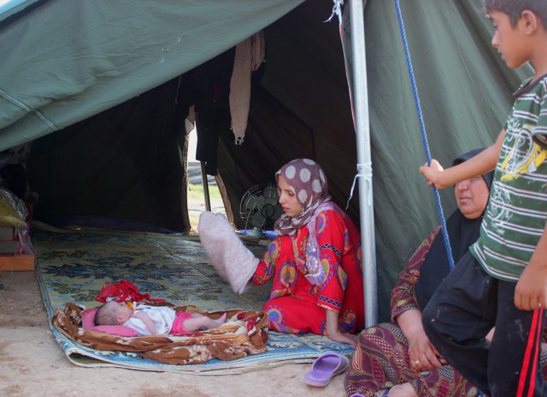 In this Sunday, July 6, 2014 photo, a displaced Iraqi family who fled from Baqouba after advances by Islamic militants, sits in their tent at a camp in Khanaqin, 90 miles (140 kilometers) northeast of Baghdad, Iraq. (AP Photo/Adam Hadei)