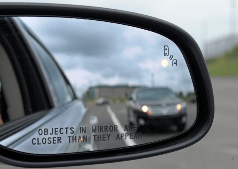 FILE - This May 22, 2012 file photo shows a side mirror warning signal in a Ford Taurus at an automobile testing area in Oxon Hill, Md. Federal officials are planning to announce Monday whether automakers should be required to equip new cars and light trucks with technology that enables vehicles to communicate with each other to prevent collisions. Such vehicle-to-vehicle communication could eventually transform traffic safety. (AP Photo/Susan Walsh, File)