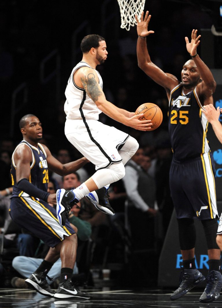   Brooklyn Nets' Deron Williams leaps for a shot between Utah Jazz's Paul Millsap (24) and Al Jefferson (25) in the first half of an NBA basketball game, Tuesday, Dec. 18, 2012, at Barclays Center in New York. (AP Photo/Kathy Kmonicek)  