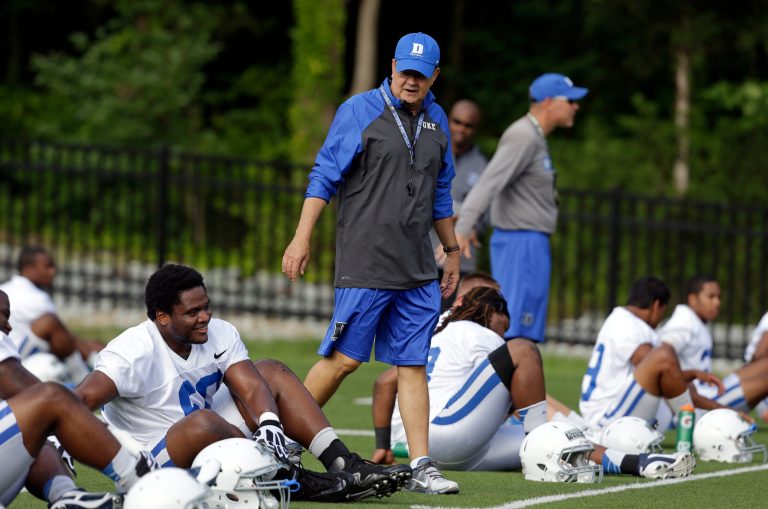 FILE - In this Monday, Aug. 5, 2013, file photo, Duke coach David Cutcliffe chats with players as they stretch during an NCAA college football practice in Durham, N.C. A growing number of college coaches are watching the social media behavior of student athletes, including Cutcliffe. (AP Photo/Gerry Broome, File)