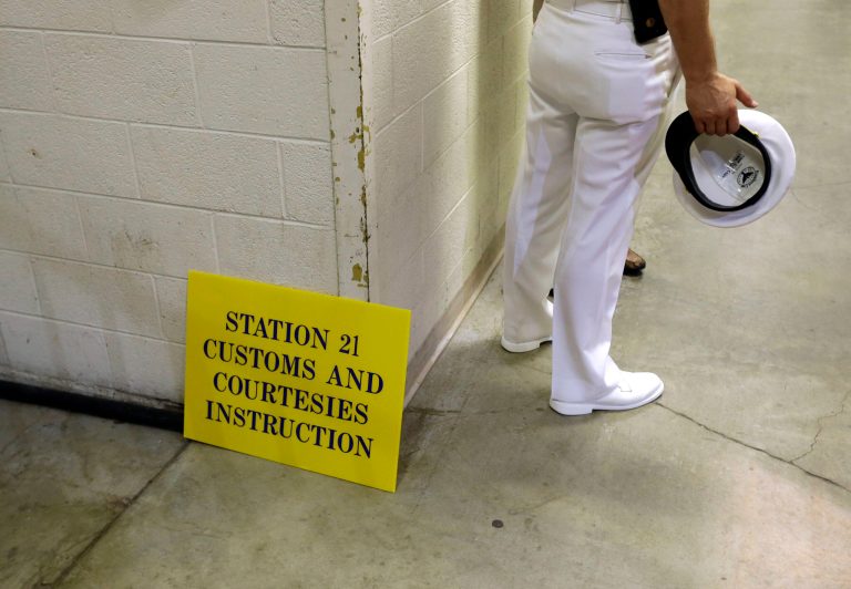 A U.S. Navy officer stands alongside a sign designating an area for prospective plebes to learn basic Navy customs and courtesies during Induction Day at the U.S. Naval Academy, Tuesday, July 1, 2014, in Annapolis, Md. More than 1,200 young men and women reported for 