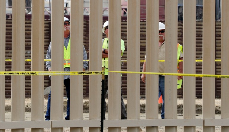 Crews look through a border wall prototype near the border with Tijuana, Mexico, Thursday, Oct. 19, 2017, in San Diego. Companies are nearing an Oct. 26 deadline to finish building eight prototypes of President Donald Trump's proposed border wall with Mexico. (AP Photo/Gregory Bull)