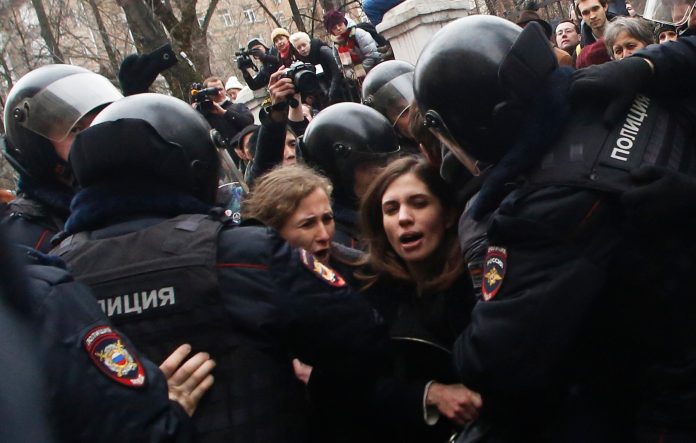 Russian police officers detain members of the Pussy Riot punk group, Nadezhda Tolokonnikova, center right, and Maria Alekhina, center left, outside a court room in Moscow, Russia, Monday, Feb. 24, 2014, where hearings started against opposition activists detained on May 6, 2012 during a rally at Bolotnaya Square. Band members are heading to Washington to promote human rights. (AP Photo/Denis Tyrin)