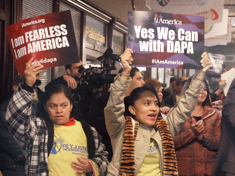 People cheer and hold up signs during a town hall forum, Tuesday, Feb. 17, 2015, in Houston. The meeting was held to help immigrants learn and prepare for President Obama's immigration order in spite of an injunction from a federal judge in Texas. (AP Photo/Pat Sullivan)