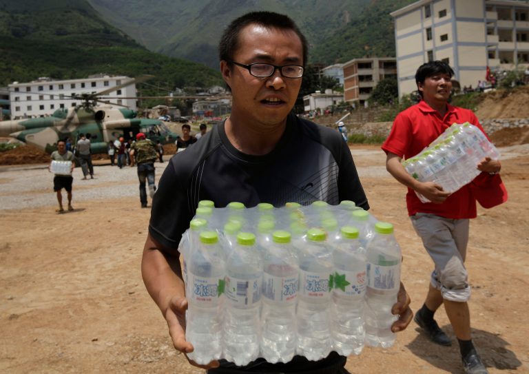 Volunteers deliver bottles of water transported by a helicopter to the earthquake hit Longtoushan town in Ludian county in southwest China's Yunnan province Wednesday, Aug. 6, 2014. Some 10,000 troops and hundreds of volunteers have rushed to Ludian to clear roads and dig out possible survivors from the debris, but landslides and bouts of heavy rains have complicated rescue efforts. (AP Photo/Andy Wong)