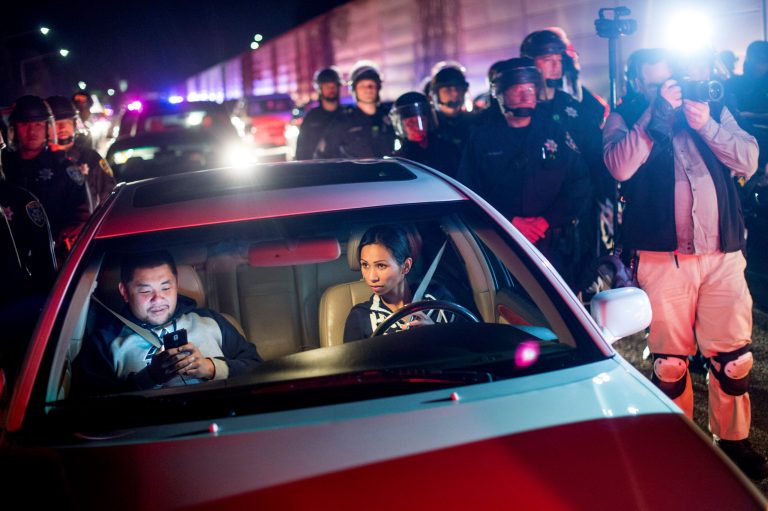 Stuck motorists wait for police to clear demonstrators from Interstate 580 in Oakland, Calif., on Monday, Nov. 24, 2014, after the announcement that a grand jury decided not to indict Ferguson police officer Darren Wilson in the fatal shooting of Michael Brown, an unarmed 18-year-old. Several thousand protesters marched through Oakland with some shutting down freeways, looting, burning garbage and smashing windows. (AP Photo/Noah Berger)