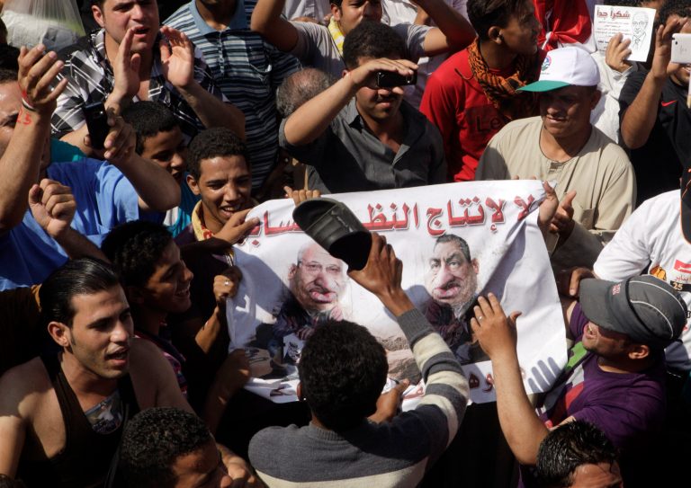   Egyptian protesters use their shoes to strike a poster showing ousted president Hosni Mubarak and presidential candidate Ahmed Shafiq, Mubarak's last prime minister, during a protest at Tahrir Square, Cairo, Egypt, Friday, June 8, 2012. Hundreds gathered in Cairo's Tahrir Square, the focal point of Egyptian uprising, to demonstrate against presidential candidate Ahmed Shafiq, Hosni Mubarak's last prime minister, ahead of a run-off vote. Arabic on the banner reads, 