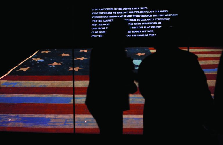 FILE - In this Nov. 21, 2008 file photo, people look at the original Star Spangled Banner, the flag that inspired the national anthem, inside a protective chamber at the National Museum of American History in Washington. Whether visitors want to try one of the first family's favorite restaurants, discover a sense of history or escape from the crowd to find a museum off the beaten path, Washington is the nation's cultural capital this weekend for inauguration visitors. (AP Photo/Jacquelyn Martin, File)