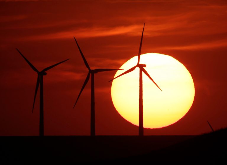 Wind turbines are silhouetted by the setting sun as they produce electricity near Beaumont, Kan., on Aug. 23. (AP Photo/Charlie Riedel, File)