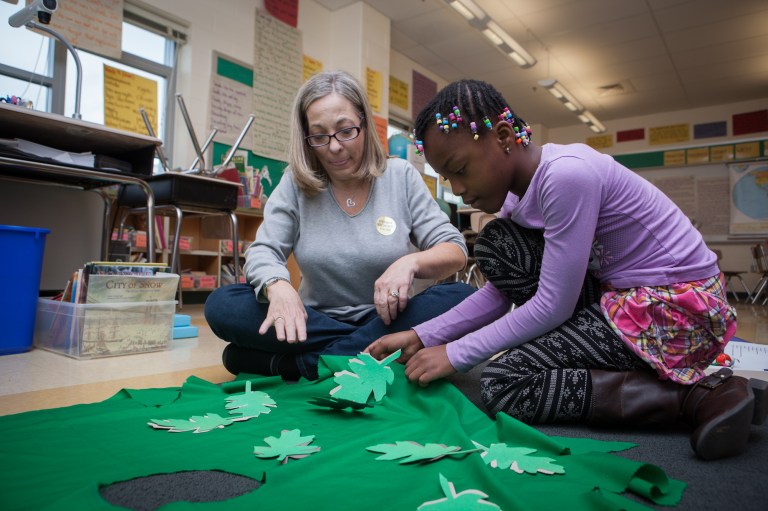 Elementary teacher Lauren Goldstein helps to make costumes with Abigail, a third grade student who is a member of the 