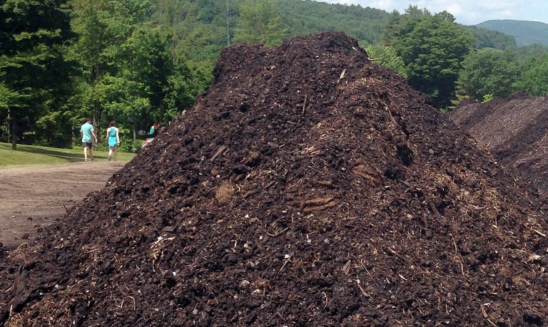 People stroll past a pile of organic products at Grow Compost of Vermont, Tuesday, June 17, 2014, in Moretown, Vt. The firm received one of this year's Working Lands grants, a share of $1.1 million that was awarded to 37 agricultural and forestry projects around the state. (AP Photo/Lisa Rathke)