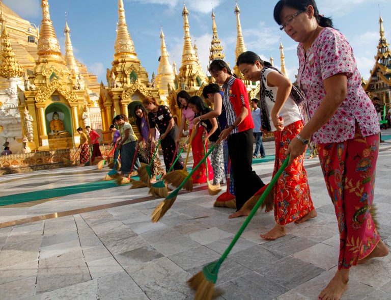In this Aug. 17, 2014 photo,  a group of Buddhist devotees sweep on platform at Myanmar famous Shwedagon Pagoda in Yangon, Myanmar. Every evening, more than a dozen men and women walk in a tight row in front of Myanmar's most revered Buddhist pagoda, sweeping the vast marble terrace in unison in hopes of keeping it clean for barefoot pilgrims. To these volunteers, this is not a chore but a noble act, one they carry out eagerly in an effort to gain merit, or spiritual credit. (AP Photo/Khin Maung Win)
