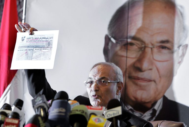   FILE - In this Sunday, June 3, 2012 file photo, Egyptian presidential candidate Ahmed Shafiq holds a clipping from an Arabic newspaper with a headline that reads, 