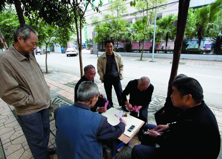 UPDATING THE CAPTION WHEN THE TRIAL STARTED - Chinese people play cards on the pavement near the Chengdu Intermediate People's Court in Chengdu in southwest China's Sichuan province Monday, Sept. 17, 2012. The trial of Wang Lijun, an ex-police chief at the center of China's worst political scandal in decades, started unexpectedly at the court Monday, a day earlier than the court had announced. At the height of his career, Wang led a police crackdown on the violent underworld in a sprawling metropolis, arresting hundreds of gangsters and government officials, some of whom were sentenced and executed in a matter of months. Now the former police chief is in the hands of the opaque Chinese justice he once brandished against others. (AP Photo/Andy Wong)