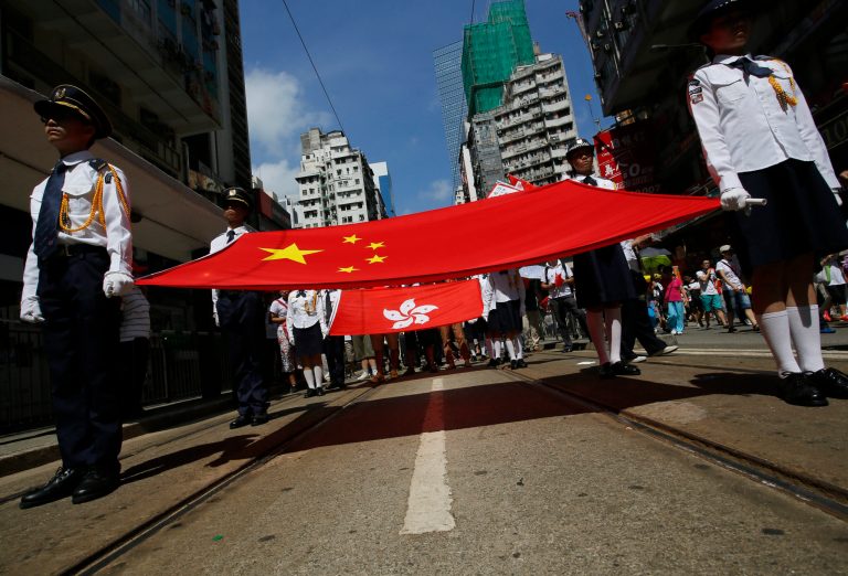 Participants hold a Chinese national flag and a Hong Kong flag as tens of thousands of people march on a down town street to oppose a planned civil disobedience campaign by pro-democracy activists in Hong Kong, Sunday, Aug. 17, 2014. The rally was organized by a pro-Beijing group. Many carried banners or shouted slogans saying they were opposed to the Occupy Central pro-democracy movement. (AP Photo/Vincent Yu)
