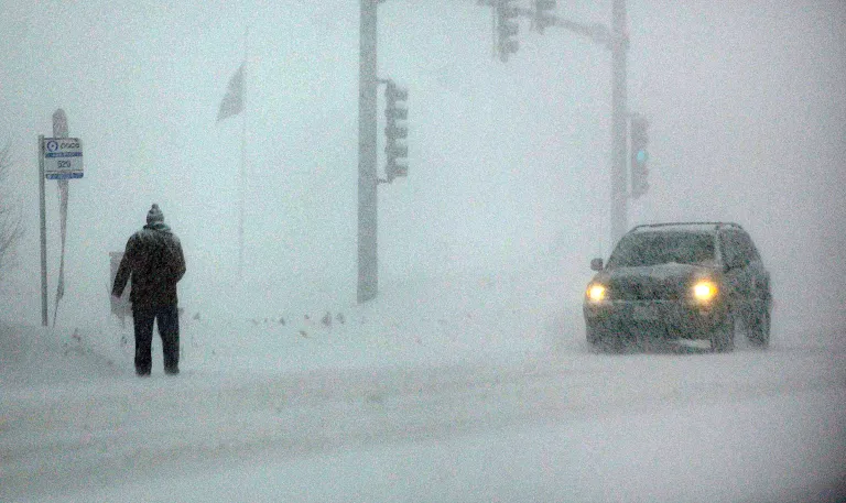A man waits at a bus stop on Randall Road near Batavia, Ill., Monday, Feb. 17, 2014. The National Weather Service on Monday forecast up to 8 inches of snow for areas of northern Illinois and 5 inches in central Illinois. (AP Photo/Daily Herald, John Starks)