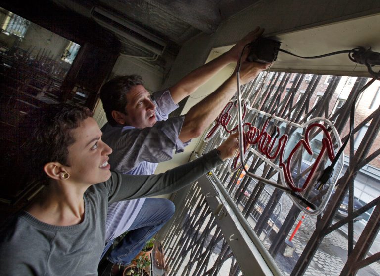   In this Tuesday, Dec. 4, 2012, photo, General Manager Ludmila Silva and proprietor Adam Weprin, of the Bridge Cafe, in New York's South Street Seaport, take down the restaurant's neon sign at the restaurant. Like many small business owners in the Northeast whose stores, restaurants, factories and offices were devastated or destroyed by the Oct. 29 storm, Weprin is hoping that federal, state and local officials will quickly come up with grants to help him rebuild and survive. (AP Photo/Richard Drew)  