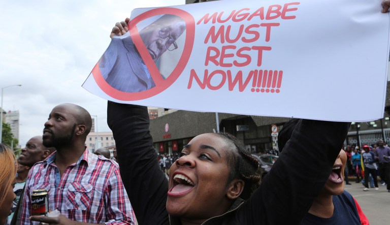 A woman holds up a banner among crowds marching on the streets of Harare, demanding the departure of President Robert Mugabe, Saturday Nov. 18, 2017. Opponents of Mugabe are demonstrating for the ouster of the 93-year-old leader who is virtually powerless and deserted by most of his allies. (AP Photo/Tsvangirayi Mukwazhi)