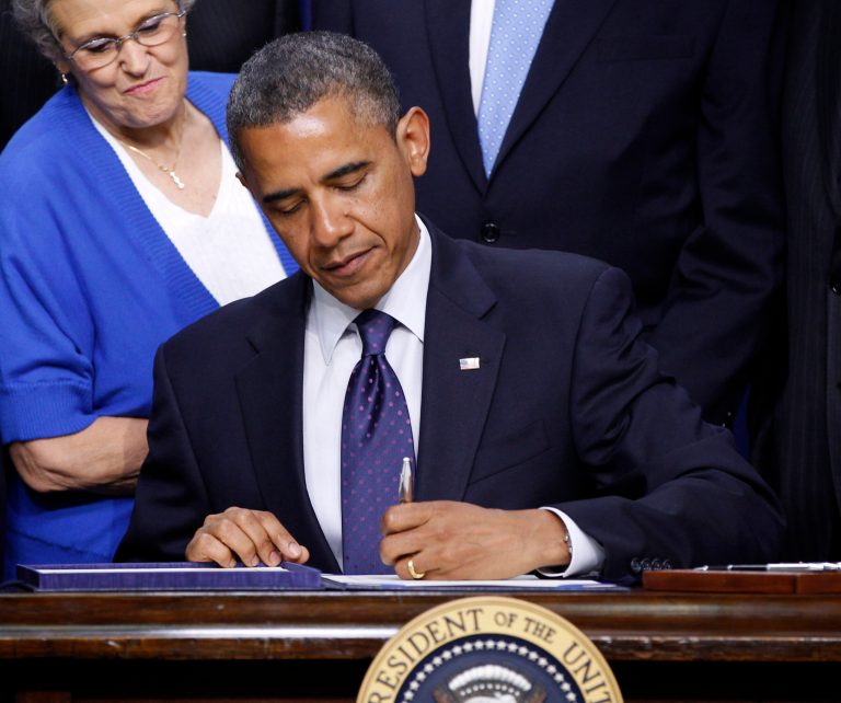 FILE - In this May 30, 2012 file photo, President Barack Obama signs the reauthorization of the Export-Import Bank Act of 2012, in the Eisenhower Executive Office Building on the White House Campus in Washington. Looking over his shoulder is  right, Sharon O'Hara, left, Executive Office Administrator, Boeing 787 Program. In his 2010 State of the Union address, President Barack Obama set a lofty national goal of doubling U.S. exports in five years. But amid a continuing manufacturing slump and weaker global economy, that goal now seems to be slipping beyond reach _ and vanishing from White House talking points. Monthly export numbers have been mostly flat or declining so far this year. And there have been four straight months of manufacturing-job losses.  (AP Photo/Pablo Martinez Monsivais, File)