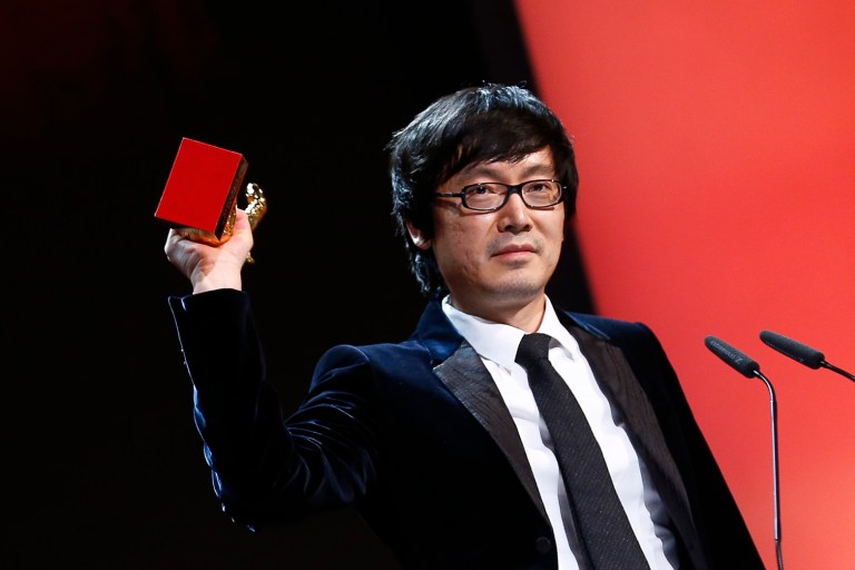 Director Diao Yinan holds aloft the Golden Bear for Best Film for the movie Black Coal, Thin Ice, during the award ceremony at the International Film Festival Berlinale in Berlin, Saturday, Feb. 15, 2014.  (AP Photo/Axel Schmidt)