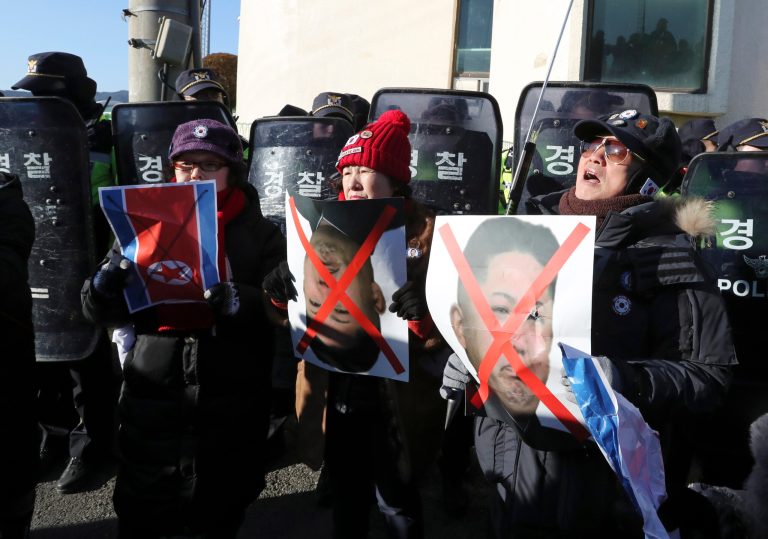Members of conservative civic group hold a picture of North Korean flag and a picture of North Korean leader Kim Jong Un as police officers stand guard before North Korea's Mangyongbong-92 ferry arrives at Mukho Port in Donghae, South Korea, Tuesday, Feb. 6, 2018. The art troupe, led by Hyon Song Wol, also the leader of the famous Moranbong girl band hand-picked by North Korean leader Kim Jong Un, will perform in Gangneung and Seoul on Feb. 8 and Feb. 11, respectively, before returning home. (AP Photo/Lee Jin-man)