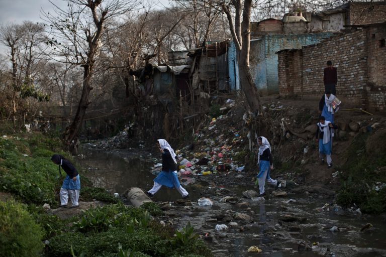 In this Tuesday, March 4, 2014, photo, Pakistani schoolgirls cross a stream of sewage and rubbish that separates their neighborhood from the main road, heading to their school in Islamabad, Pakistan. Malala's struggle for girls to be educated in a deeply conservative society led to her shooting by the Taliban two years ago, while her relentless campaign for women's was rewarded Friday, Oct. 10, by the recognition of her work as she was jointly awarded the Nobel Peace Prize. (AP Photo/Muhammed Muheisen)