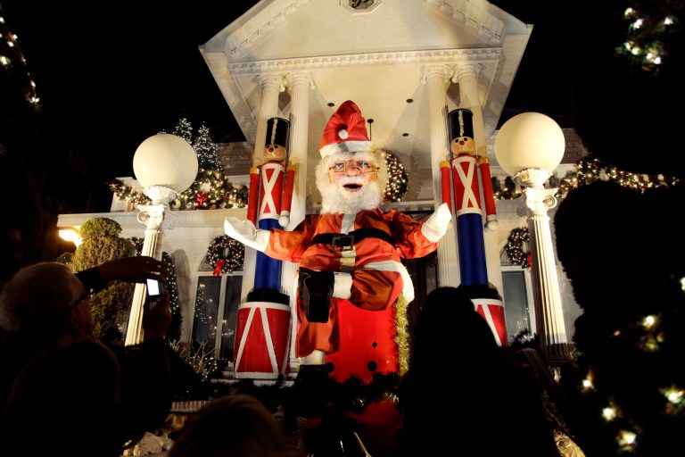   This Dec. 4, 2012 photo shows spectators viewing a a giant Santa Claus at a decorated home in the Brooklyn borough of New York. Each holiday season, tour operator Tony Muia takes tourists from around the world on his âChristmas Lights & Cannoli Tourâ visiting the Brooklyn neighborhoods of Dyker Heights and Bay Ridge, where locals take pride in over-the-top holiday light displays. (AP Photo/Seth Wenig)  