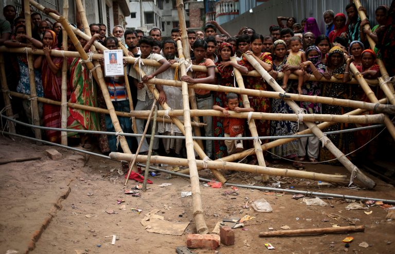 Curious onlookers and relatives of missing victims watch from behind a make shift fence as workers start dislodging parts of the garment factory building which collapsed in Savar, near Dhaka, Bangladesh on Monday April 29, 2013. Rescue workers in Bangladesh gave up hopes of finding any more survivors in the remains of a building that collapsed five days ago, and began using heavy machinery on Monday to dislodge the rubble and look for bodies - mostly of workers in garment factories there. At least 381 people were killed when the illegally constructed, 8-story Rana Plaza collapsed in a heap on Wednesday morning along with thousands of workers in the five garment factories in the building.(AP Photo/Wong Maye-E)