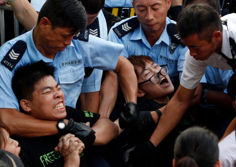 Protesters are taken away by police officers after hundreds of protesters staged a peaceful sit-ins overnight on a street in the financial district in Hong Kong Wednesday, July 2, 2014, following a huge rally to show their support for democratic reform and oppose Beijing's desire to have the final say on candidates for the chief executive's job. (AP Photo/Kin Cheung)