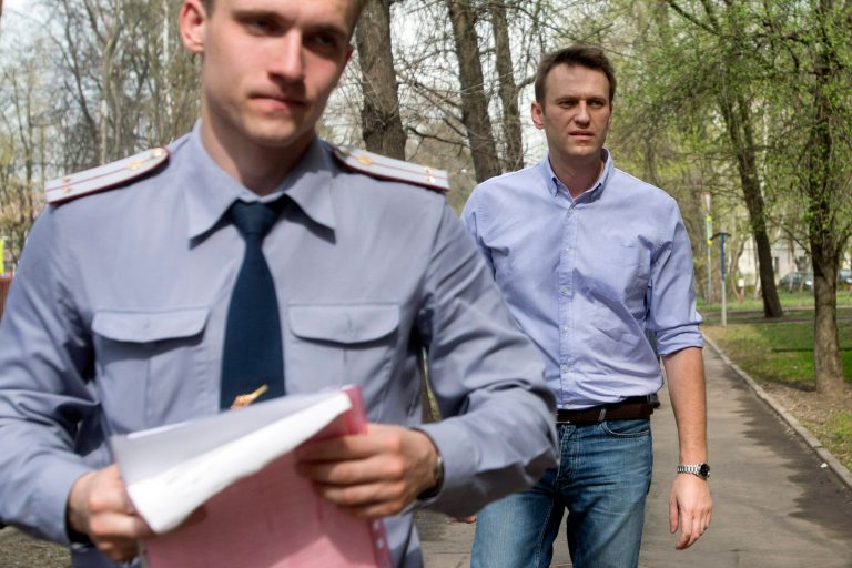 Russian opposition activist and anti-corruption crusader Alexei Navalny, right, is escorted  to a court by a policeman, left, from his  home, where he is currently staying under house arrest in Moscow, Russia, Tuesday, April 22, 2014. Russian opposition leader and anti-corruption crusader Alexei Navalny was found guilty in a libel case and fined US$8,400 in a court ruling that left the door open for his subsequent jailing. (AP Photo/Pavel Golovkin)