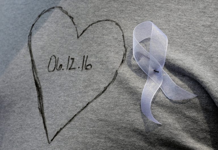 Josh Mercer wears a T-shirt Monday, June 13, 2016, in honor of two of his friends who were killed during a fatal shooting at Pulse Orlando nightclub in Orlando, Fla. (AP Photo/Chris O'Meara)