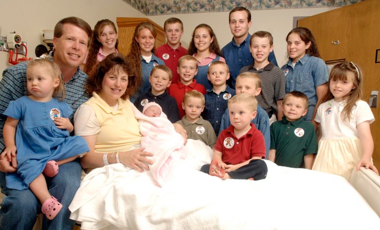 In this Aug. 2, 2007 file photo, Michelle Duggar, left, is surrounded by her children and husband Jim Bob, second from left, after the birth of her 17th child in Rogers, Ark. (AP Photo/ Beth Hall, File)