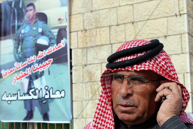 In this Jan. 3, 2015 file photo, Safi Yousef al-Kaseasbeh, the father of the Jordanian pilot 1st Lt. Mu'ath al-Kaseasbeh, speaks on his mobile phone, while standing by a poster of his son at a gathering of his family in Karak, south of Amman, Jordan. (AP Photo/Raad Adayleh, File)