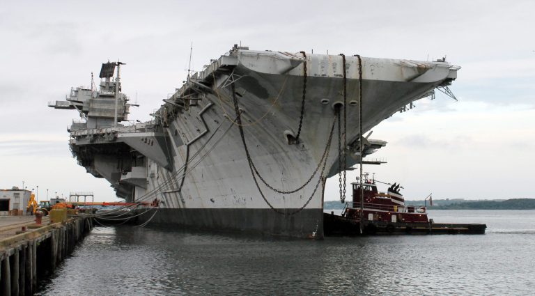 In this photo released by the U.S. Navy, a tug works alongside the decommissioned aircraft carrier USS Saratoga at Naval Station Newport Thursday, Aug. 21, 2014 in Newport, R.I. The ship departed port Thursday for it's final journey to the Esco Marine ship recycling plant in Brownsville, Texas, where it will be scrapped.  (AP Photo/U.S. Navy)
