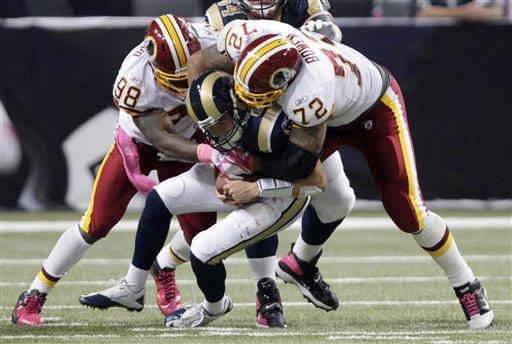 St. Louis Rams quarterback Sam Bradford, center, is sacked for a 2-yard loss by Washington Redskins defenders Brian Orakpo, left, and Stephen Bowen during the second quarter of the NFL football game Sunday, Oct. 2, 2011, in St. Louis. 