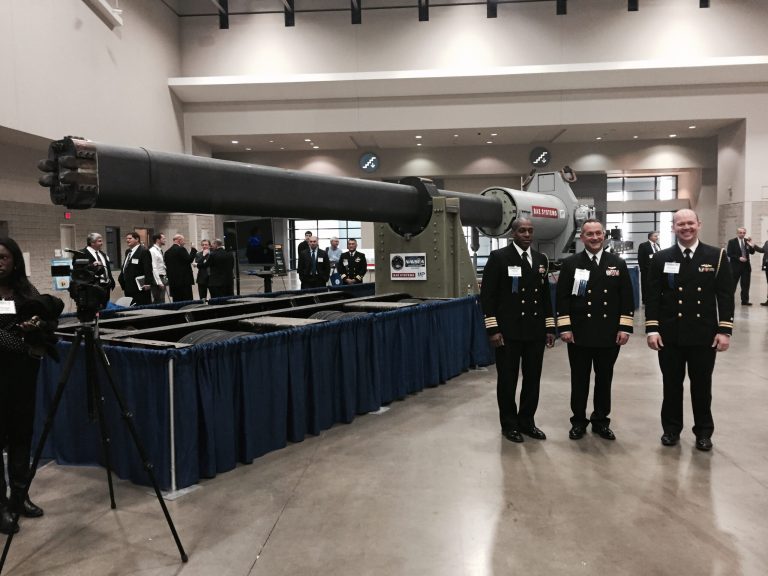 Chief of Naval Research Rear Adm. Mat Winter (center) poses in front of one of two variants of the Navy's new rail gun in Feb. 4, 2015. The gun will undergo its first shipboard testing next year. (Graeme Jennings/Examiner)