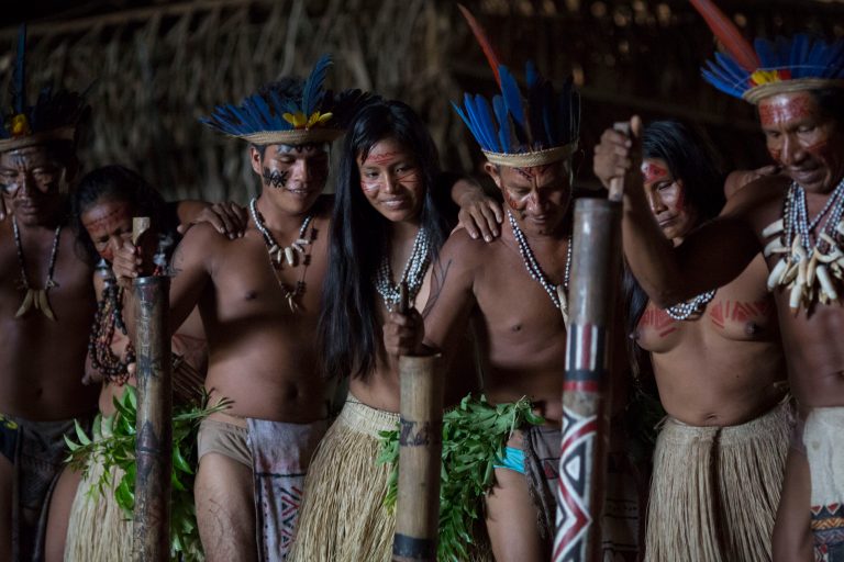 In this May 24, 2014, photo, men and women from various tribes dance in the Tatuyo indigenous community near Manaus, Brazil. The community of thatched palm roofed houses is home to nine families who moved to the riverside plot some 15 years ago from deep inside the rainforest. While they normally wear the shorts, t-shirts and flip-flops that are standard fare throughout Brazil, the villagers change into their ceremonial finest to receive tourists. (AP Photo/Felipe Dana)