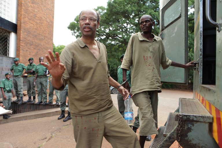 Former US Congressman Mel Reynolds, centre left, prepares to enter a prison truck while handcuffed  following his court  appearance at the magistrates courts in Harare, Thursday, Feb.  20, 2014. Reynolds was arrested  in Zimbabwe for allegedly possessing pornographic material and violating immigration laws.  (AP Photo/Tsvangirayi Mukwazhi)