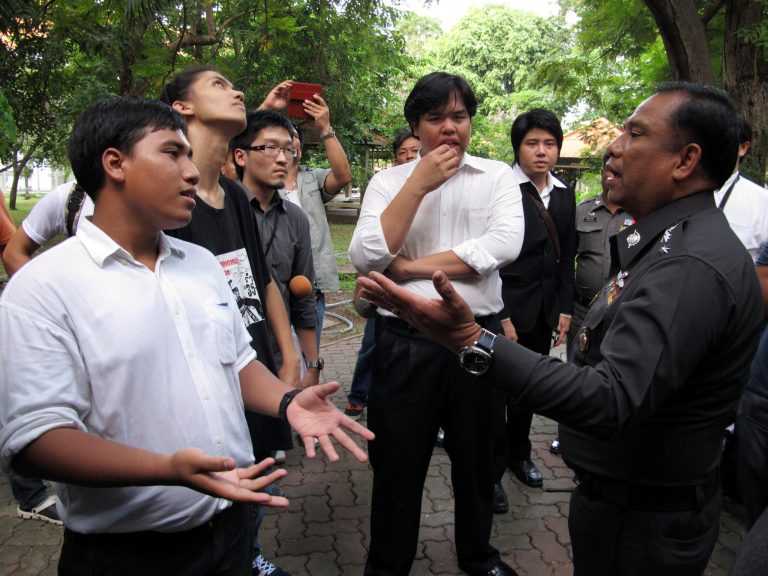 In this picture take Thursday, Sept. 18, 2014.Advance for story Thailand-Academic Freedomâ by Thanyarat Doksone.Three students--Sirawit Serithiwat, left, Ratthapol Supasopon, second on the left, and Worawut Butrmatr, fourt from the left--negotiated with deputy provincial police chief Col. Surasak Khunnarong to let an academic seminar go on at Thammasat University, Rangsit Campus, in Pathum Thani, Thailand, Two days earlier, an army regiment asked the university for its cooperation to cancel the event to prevent divisiveness in the country.(AP Photo/Thanyarat Doksone)