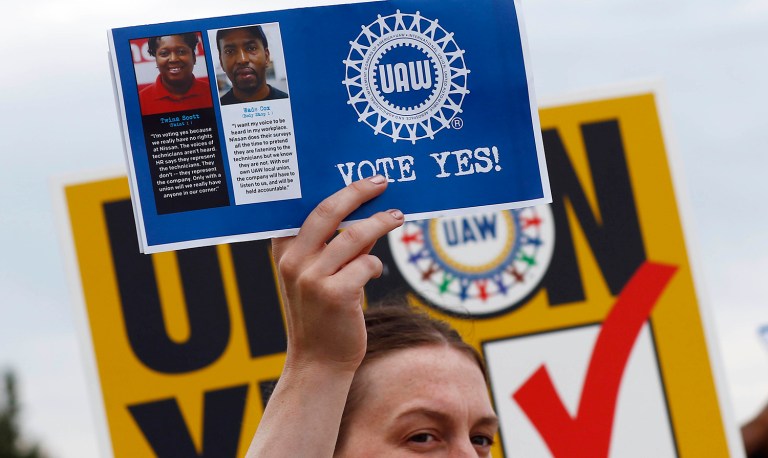 In this Tuesday, Aug. 1, 2017, photo, a UAW member holds up a flyer to be given to Nissan workers as they leave the Nissan vehicle assembly plant in Canton, Miss. Union members met most shifts arriving and leaving waving posters, flyers and singing union chants at each of the plant's employee entrances. In voting that begins early Thursday, Aug. 3, some 3,700 direct employees at Nissan Motor Co.'s car and truck assembly plant in Canton will decide whether they want a union. The polls close at 7 p.m., local time on Friday. (AP Photo/Rogelio V. Solis)