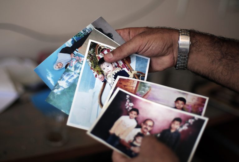 In this Wednesday, Aug. 13, 2014 photo, Mouin Quishta holds photographs of his daughter Shahed, 8, who was killed on July 22, in the town of Beit Lahiya, northern Gaza Strip. Almost a month after her death from what her father says was an Israeli tank shell, her family remains paralyzed by grief. (AP Photo/Khalil Hamra)