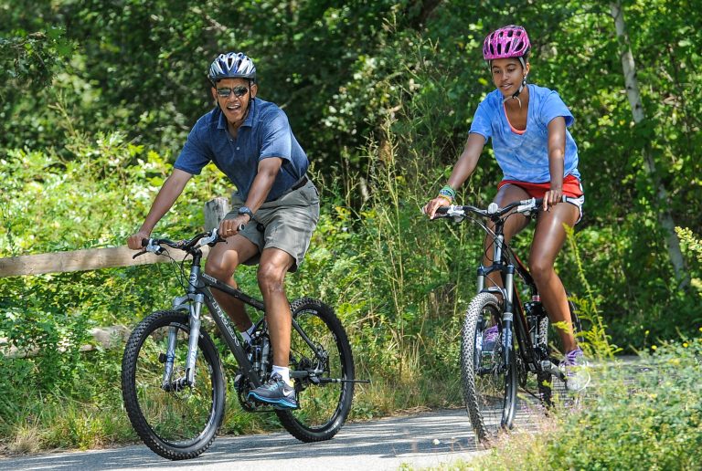 President Barack Obama, left, his daughter Malia Obama ride a bike during a vacation on Martha's Vineyard August 16, 2013 in West Tisbury, Mass. (Photo by Rick Friedman-Pool/Getty Images)
