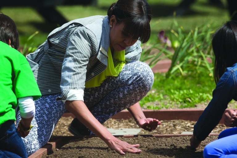 Pablo Martinez Monsivais/AP
First lady Michelle Obama smoothes out the dirt as she plants wheat seedlings with fifth graders Ariana Docanto, right, from Arthur D. Healey School in Somerville, Mass., and Emilio Vega, left, from Benjamin David Gullett Elementary School in Bradenton, Fla., during the spring planting of the White House garden Thursday.