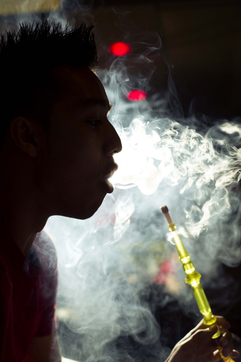 A person smokes a hookah in a 2013 photo in Troy, Mich. Dearborn, a Detroit suburb known for an abundance of hookah cafes, has ordered that no new ones be opened in the next six months. Dearborn Mayor Jack O'Reilly Jr. said Monday, Aug. 18, 2014 that his city is not targeting its 15 licensed hookah cafes, but the additional 15 or so cafes that do not have licenses.(AP Photo/Detroit Free Press, Jarrad Henderson)