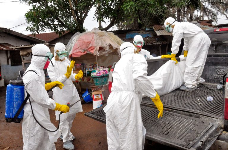 Health workers carry load the body of a woman that they suspect died from the Ebola virus, onto a truck in front of a makeshift shop in Monrovia, Liberia, Wednesday. A surge in Ebola infections in Liberia is driving a spiraling outbreak in West Africa that is increasingly putting health workers at risk as they struggle to treat an overwhelming number of patients. (AP Photo/Abbas Dulleh)