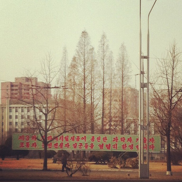 In this photo posted on Instagram, a man walks in Pyongyang, North Korea, under a new roadside banner referring to North Korea's controversial Feb. 12 nuclear test Monday, Feb. 25, 2013. Tweeting and uploading to Instagram is pretty ordinary stuff in the world of social media, but revolutionary for North Korea. (AP Photo/Jean H. Lee)