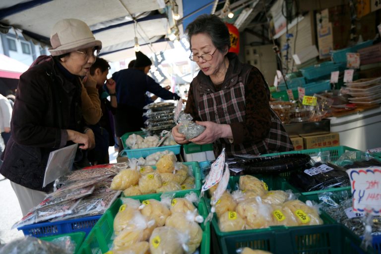 A shop clerk, right, explains a product to a customer, left, at a dry fish store at a fish market in Tokyo, Tuesday, April 8, 2014. Japan's central bank has refrained from expanding its ultra-loose monetary policy despite a sales tax hike, saying the economy is recovering moderately. The Bank of Japan's policy statement Tuesday was the first since an April 1 increase in the sales tax, to 8 percent from 5 percent, that is expected to stall economic growth in coming months as consumers adjust to higher costs. (AP Photo/Eugene Hoshiko)