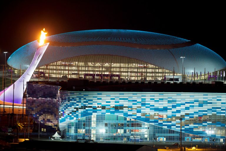 The Olympic Cauldron, left, is lit during a test between the Bolshoy Ice Dome, top, and the Iceberg Skating Palace, foreground, early Thursday morning, Feb. 6, 2014, in Sochi, Russia, prior to the start of the 2014 Winter Olympics. (AP Photo/Pavel Golovkin)