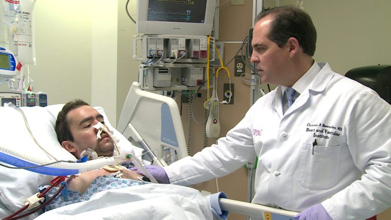 This handout photo provide by the University of Pittsburgh Medical Center, taken March 5, 2014, shows  Dr. Christian Bermudez of the University of Pittsburgh Medical Center checking patient Jon Sacker, who was being treated with an experimental device called the Hemolung that acts like dialysis for lungs. Doctors credit the experiment with buying Sacker time to improve enough to undergo a lifesaving double lung transplant later that month. (AP Photo/University of Pittsburgh Medical Center)