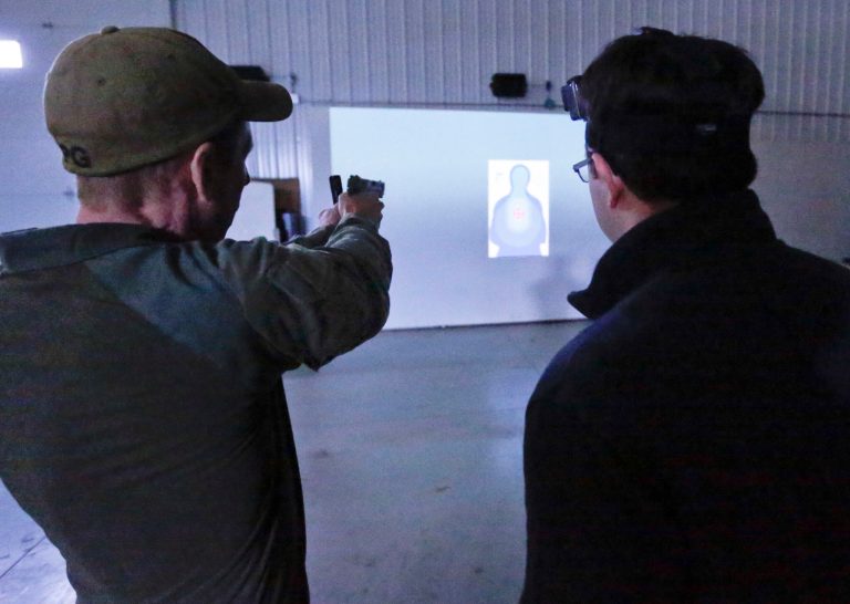 Gregg Frankhouser, an FBI special agent, left, shows a reporter how a modified pistol is aimed calibrated for use in a simulation before participating in a media day demonstration at a training facility in Monroeville, Pa., Thursday, Feb. 22, 2018. The FBI said they use the simulations to give schools, businesses and churches insights in the event they encounter an active shooter situation. Participants are given a modified pistol that shoots a laser to use in the simulation. (AP Photo/Keith Srakocic)